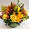 Bouquet of yellow roses, tulips, and lilies in a green striped vase