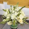 White and pale yellow floral arrangement in a green vase