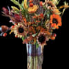 Autumn bouquet with sunflowers and orange blooms in a clear glass vase