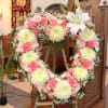Heart-shaped floral wreath with pink and white flowers on an easel