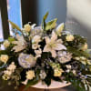 White lilies and pale roses arranged with blue hydrangeas in a low vase