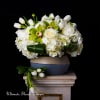 White roses and tulips arranged in a low vase with green orchids