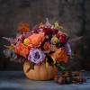 Autumn bouquet in a pumpkin-shaped vase with roses and mixed blooms