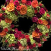 Circular floral wreath with roses and hydrangeas in pink, orange, and green