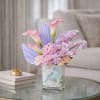 Pink calla lilies and lavender orchids in a glass vase