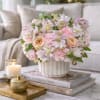Blush and cream floral arrangement in a white vase on a table