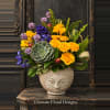 Colorful bouquet in a sculpted ceramic vase with a face design