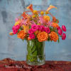 Bright orange and pink floral arrangement in a clear glass vase