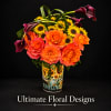 Bouquet of orange roses, sunflowers, and dark calla lilies in a printed tin container