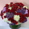 Large bouquet of red roses, white hydrangeas, and purple hydrangeas in a glass vase
