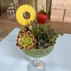 Succulent arrangement in a stemmed glass with a pineapple ring and strawberry garnish