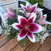 Pink and white lilies arranged in a glass vase with baby's breath