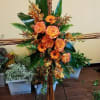 Tall floral arrangement with orange roses and gerbera daisies on bamboo supports