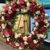 Large floral wreath with red, pink, and white blooms on a black stand