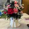 Pink and black floral arrangement in a ghost-shaped vase with butterfly accents