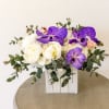 White and purple floral arrangement in a white wooden box