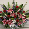 Large bouquet of pink lilies, red roses, and purple flowers in a white vase