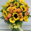 Bouquet of yellow sunflowers and peach roses in a glass vase