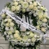 White floral funeral wreath with a memorial ribbon on an easel