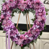 Heart-shaped pink and purple floral wreath on an easel with a ribbon bow