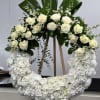 White rose and hydrangea wreath on an easel with dark green leaves