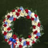 Circular floral wreath with red, white, and blue flowers on a stand