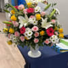 Large mixed flower arrangement in a white pedestal vase