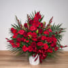 Red roses and lilies in a white vase with a red ribbon