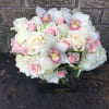 White and pink bouquet with roses, orchids, and hydrangeas in a black vase