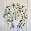 White daisy wreath on a stand with a white ribbon