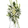 White and pale yellow funeral spray on a metal easel