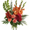 Tall orange and red floral arrangement in a clear glass vase
