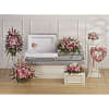 Pink floral funeral display around a white casket