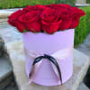 Red roses arranged in a lavender hat box with a ribbon bow