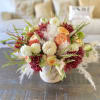 Beautiful fall season blooms mixed with small pumpkins and pampas grass. The