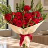Red flower bouquet wrapped in beige paper with a red ribbon