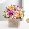 Arrangement of peach roses and pink flowers in a wooden box