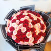 Large bouquet of red and blush pink roses wrapped in black paper