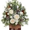 White roses and pinecones in a brown container with evergreen accents