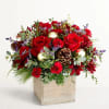 Red roses and burgundy flowers in a wooden box with pinecones