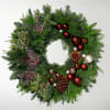 Christmas wreath with evergreen branches, red ornaments, and pinecones
