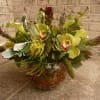 Low arrangement of green cymbidium orchids and pale calla lilies in a clear glass bowl vase