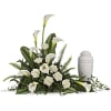 White calla lilies and roses arranged beside a white urn