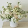 Pastel floral arrangement in a white vase with cream and blush blooms