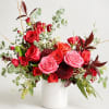 Red and pink roses arranged in a white vase