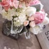 Pink and white rose bouquet in a glass vase with a butterfly pick