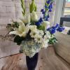White lilies, roses, daisies, and blue flowers in a dark blue vase