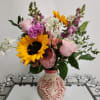 Mixed bouquet with sunflowers, pink roses, and purple blooms in a decorative vase