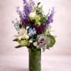 A tall, airy garden-style arrangement rises gracefully from a clear cylinder vase