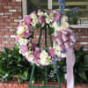 Floral wreath on an easel with pink, white, and blue flowers and a lavender ribbon